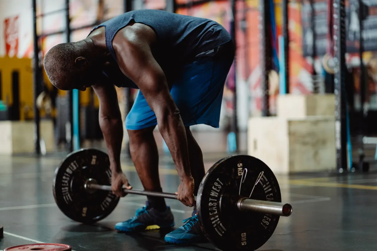 An athlete setting up a barbell deadlift in a gym.